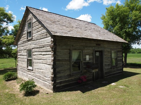 A June 16, 2013 photo of the Slattum Cabin. Note the gable end elevation, and compare the seams of the log cabin with the seams of the gable elevation in the 1950s photo. They are the same.