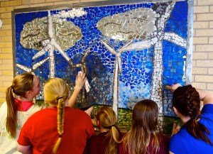 Teacher Mindi Paulson (far right) leads students in grouting the public wind turbine mosaic at the Langdon Elementary School.