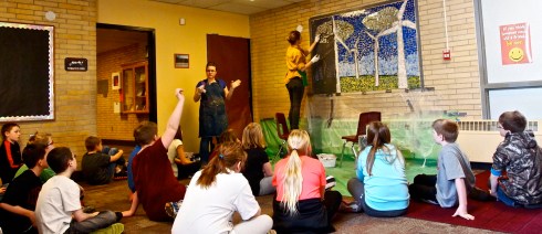 Teacher Mindi Paulson explains the process of grouting to the students as Molly McLain grouts.